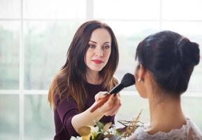 Make-up artist doing make up for young beautiful bride photo