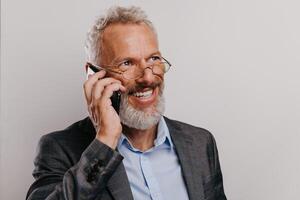 Portrait of happy mature businessman in formalwear texting on smart phone against white background photo