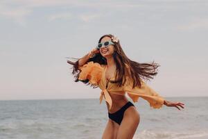 Attractive young woman in swimwear running and looking happy while enjoying day seaside photo