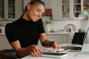 Busy young woman talking on mobile phone and smiling while working at home photo