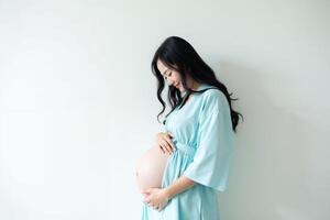 photo of pregnant woman standing against white wall background,