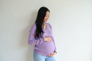photo of pregnant woman standing against white wall background,