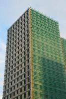 A multi-storey residential building under construction against the blue sky. A fragment of the facade of modern urban architecture. photo