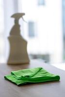 cleaning agent in white spray bottle on table, house cleaning concept against clean window photo