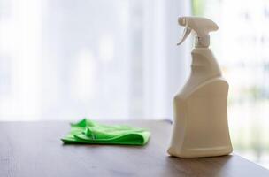 cleaning agent in white spray bottle on table, house cleaning concept against clean window photo