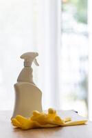 cleaning agent in white spray bottle on table, house cleaning concept against clean window photo