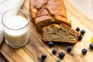 glass of milk and sweet homemade banana bread with crispy crust on a wooden board, dessert photo