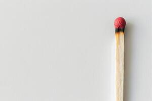 Minimalist image of a single matchstick with a red tip on a white background Concept of simplicity, ignition, fire, safety. Copy space photo
