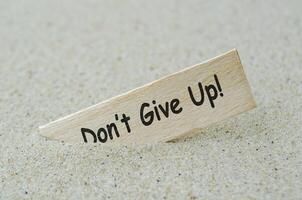 Do not give up text on wooden stick with beach sand background. Motivational concept photo