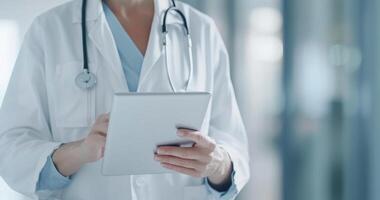 A professional doctor interacts with a tablet computer, reviewing patient information in a hospital photo