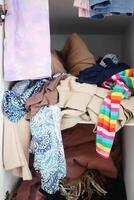 Messy closet with piled clothes and colorful accessories, displaying chaos and disorder in storage photo