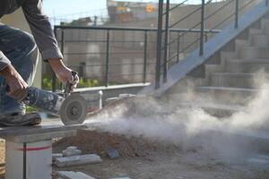 A man is using a grinder to cut a piece of concrete photo