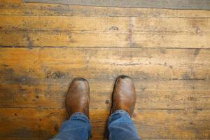 Stylish Casual Brown Boots Resting on a Rustic Wooden Floor with Natural Warmth and Texture photo