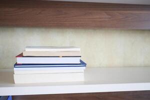 An open book with its pages gently turning rests on a wooden table in the breeze photo