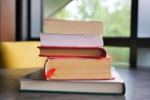 An open book with its pages gently turning rests on a wooden table in the breeze photo