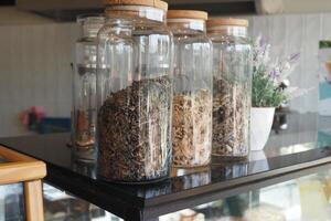 A detailed view of various jars filled with herbs and spices in a warm kitchen or cafe atmosphere photo