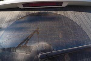 A Dusty Automobiles Rear Window Displaying a Unique Circular Pattern of Dirt and Grime photo