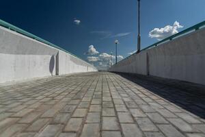 Paving slabs on a pedestrian bridge. The bridge is nearby. Clouds in the sky photo