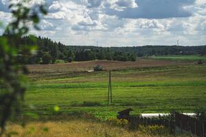 A combine harvester in the distance reaps wheat in a field photo