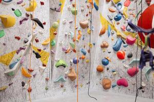 Interior shot of indoor climbing centre without people with assortment of colorful and challenging climbing walls. White wall with climbing holds in gym. photo