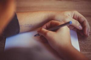 Student cheating during exam in university, reading cheat sheet with formula written on hand photo