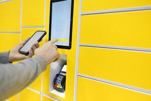 Close up of a man picks up mail from automated self-service post terminal machine photo