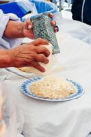 Woman preparing cheese for cook using cheese grater in the kitchen photo