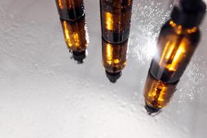 Group of bottles with drops on them and their reflection on a mirror surface photo