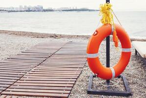 The lifebuoy is fixed on a support on a pebble beach. photo