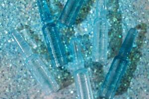 Blue ampoules with intense moisturizing concentrate with hyaluronic acid and vitamins on shiny sparkling background. photo