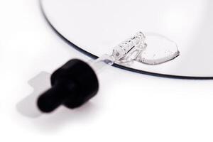 Close up of gel or serum glass pipette with transparent drops on white background. photo