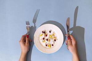 Tablets, pills and capsules on a white porcelain plate. The table is set with a plate photo