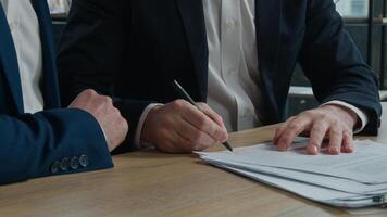 Close-up two unrecognizable businessmen men business partners signing contract document conclude successful financial deal at meeting in office sign for partnership cooperation shake hands handshake photo