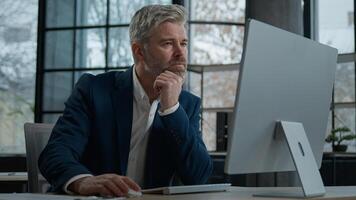 Mature focused thoughtful caucasian businessman marketing specialist working on computer in office man entrepreneur manager thinking analyzing finance digital data in Internet creating online project photo