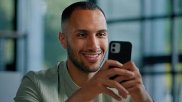 African American businessman browsing smartphone indoors. Multiracial man in office using mobile phone app networking male employer entrepreneur chatting with internet website searching net online photo