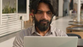 Concentrated serious indian man busy focused businessman office worker manager employee typing laptop working online with computer thinking problem talking via call remote business negotiation photo