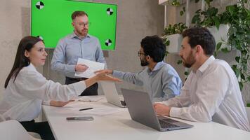 Male leader speaker coach talking to team multiracial men listen to CEO businessman teaching employees showing business presentation at group conference pointing at green interactive board chroma key photo
