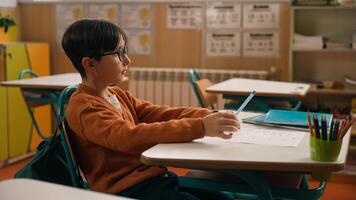 School class lesson clever concentrated Caucasian boy son child schoolboy kid studying learning in classroom write test exam task study learn primary education write knowledge classwork at table desk photo
