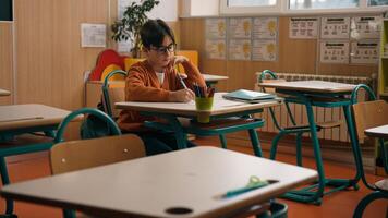 Alone little boy in empty school class room sitting at desk table writing homework clever Caucasian primary school child kid son pupil learning task write notes lesson studying elementary education photo