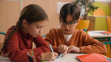 Two Caucasian pupils classmates in school lesson class together write little boy help girl kid child with test homework helping explain task studying children education learning learn teamwork friends photo