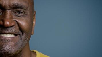 Close-up half male face with joyful expression mature african american man looking at camera smiling white healthy toothy smile happy customer satisfied with service posing in gray background studio photo