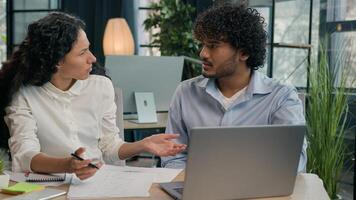 Arabian businesswoman mentor explain financial data teach employee consult trainee help with web project on laptop Indian silly businessman client not understand difficult business learning in office photo