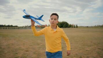 Happy Caucasian little boy child son teen kid offspring schoolboy run playing active game toy flying plane launching airplane running play pretend dreaming pilot fresh air ecology village park nature photo