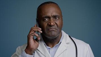 Mature african american man doctor talk on phone with patient close-up puzzled male medical consultant in white coat consult client by smartphone give negative answer say no remote healthcare service photo