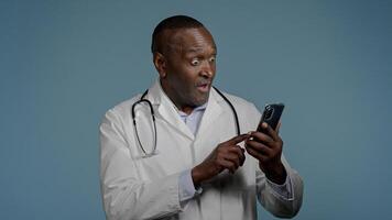 African American man doctor receive sms message on mobile phone reading good news from patient smiling male medical employee celebrating victory rejoicing success recovery excellent analysis results photo