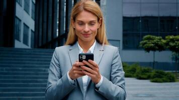 Young woman stand on downtown with phone in hands typing business email answering message in social media smiling businesswoman using mobile application for remote internet communication on smartphone photo