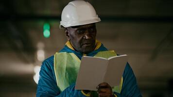 Mature man professional worker engineer builder with protective helmet inspects room writes data in notebook concentrated experienced foreman creates plan for construction of building writing notes photo