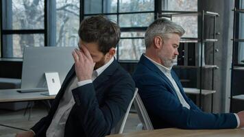 Upset shocked caucasian men businessmen partners employees sitting in office frustrated with business failure think about financial problem depressed entrepreneurs colleagues have trouble feel worried photo