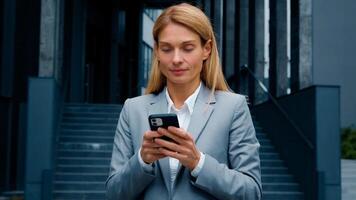 Young woman stand on downtown with phone in hands typing business email answering message in social media smiling businesswoman using mobile application for remote internet communication on smartphone photo