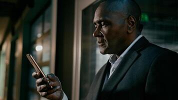 Close-up smiling happy african american man using mobile phone browsing email checking message read good news social media network on smartphone ethnic businessman talking on call on cellphone photo